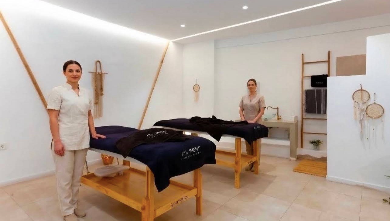 Two massage professionals in a bright couples treatment room at The Moment