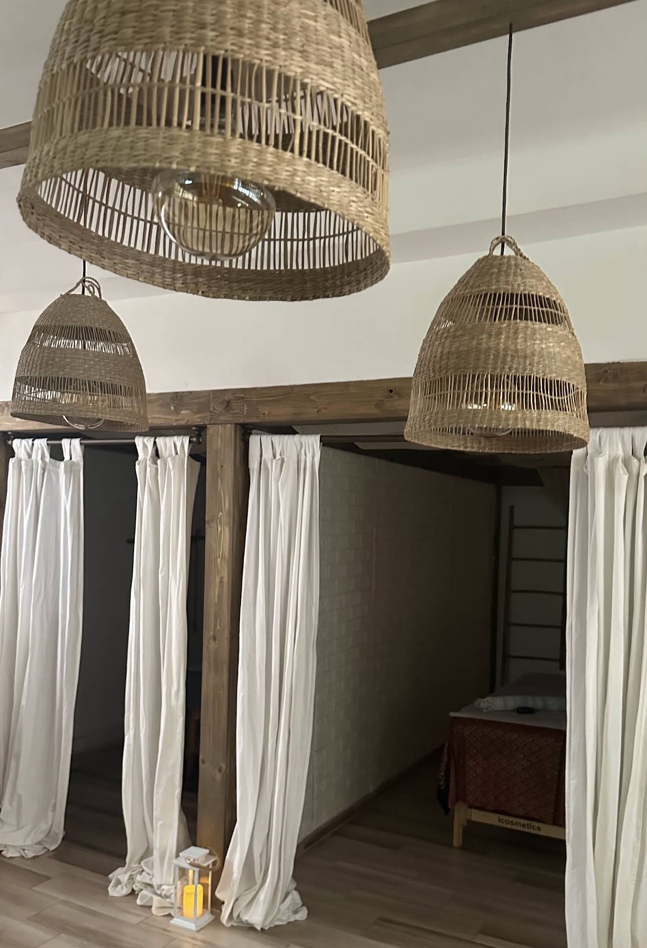 Private curtained massage spaces beneath woven lights